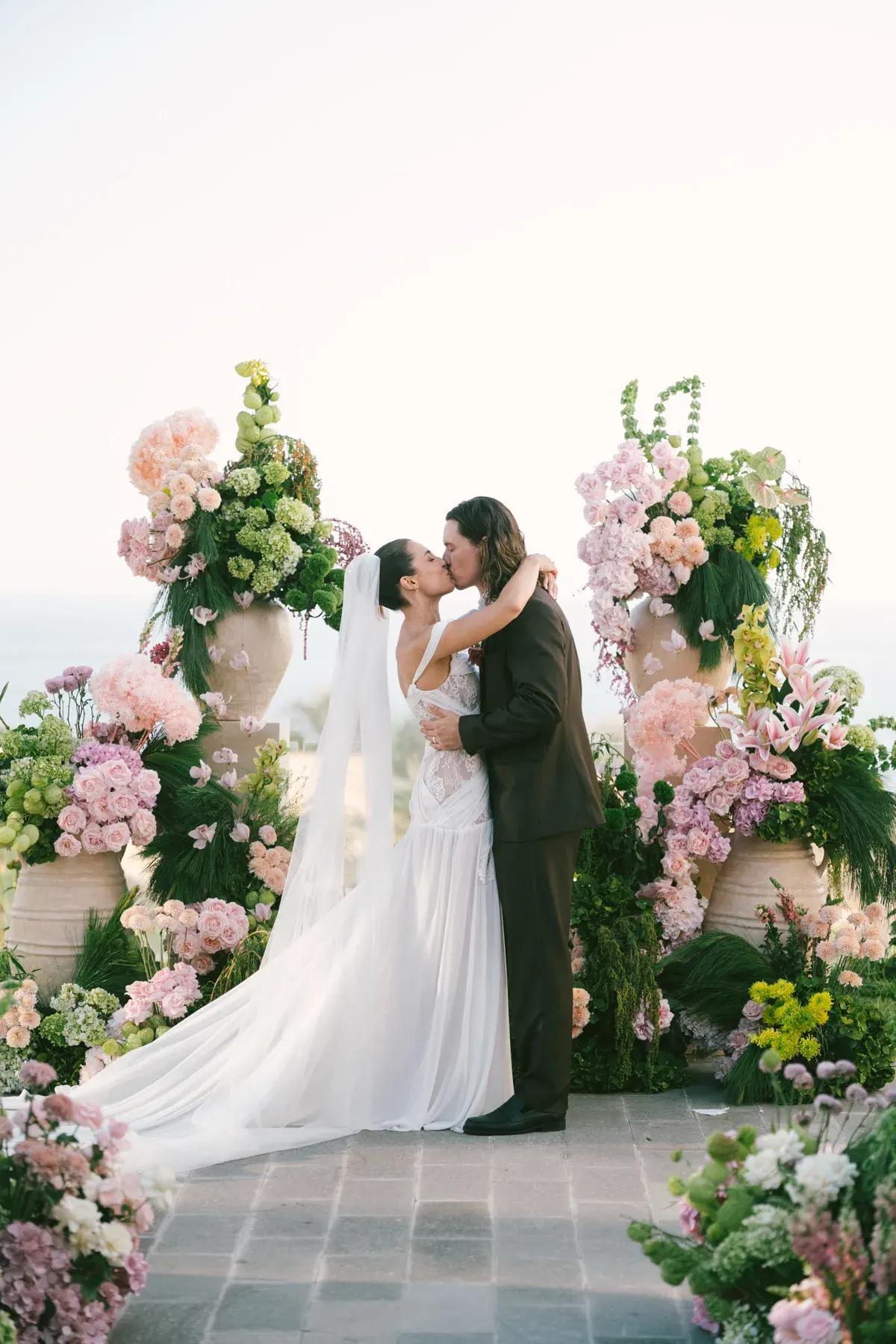 A first kiss at a floral ceremony arch