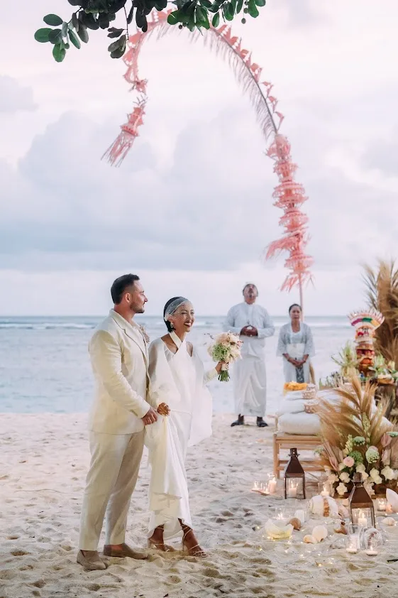 A ceremony on the beach beneath a flowing floral arch